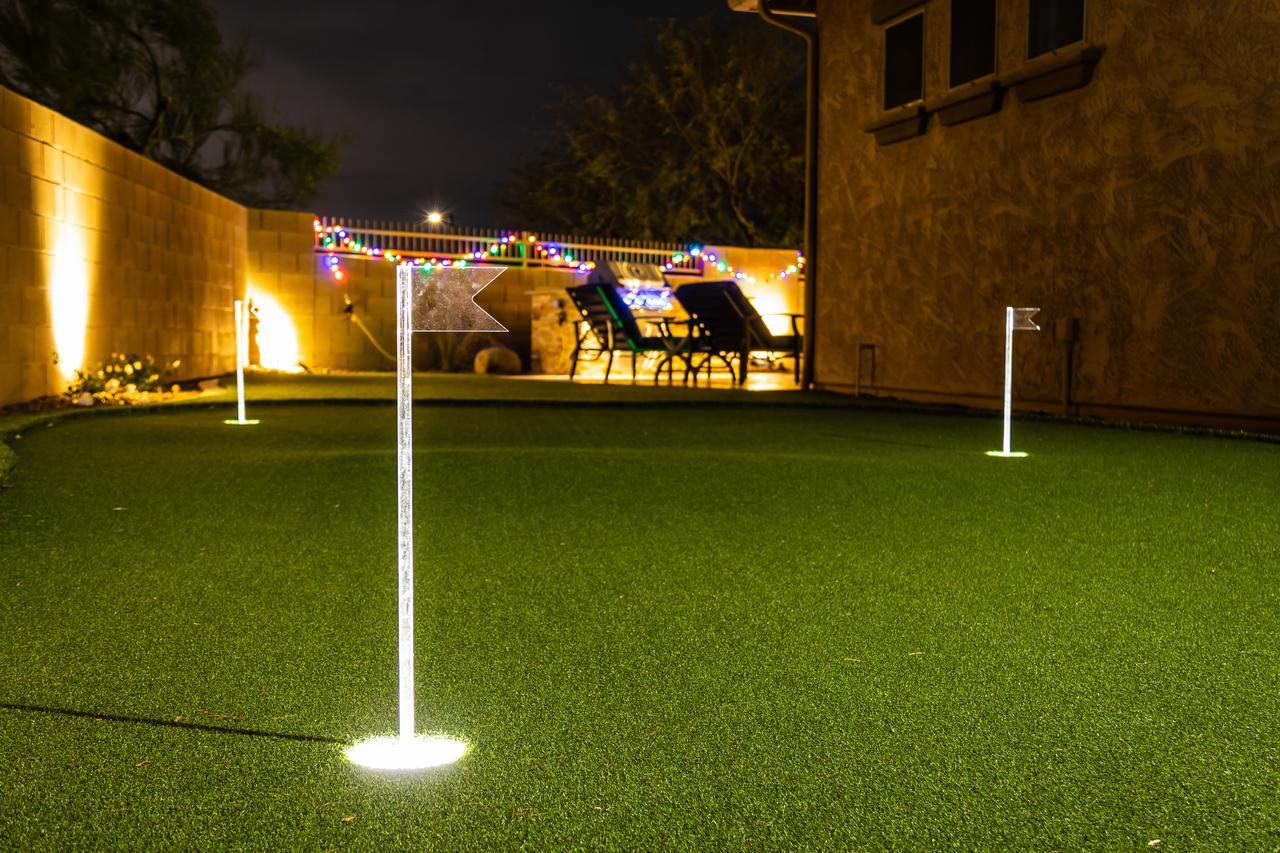 Finished artificial turf putting green installation with illuminated flagsticks at night